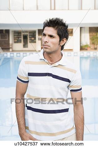 Stock Photo - Close-up of a young man standing at the poolside. Fotosearch