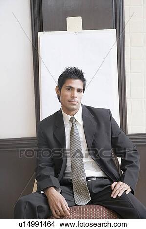 Portrait of a businessman sitting in front of a whiteboard and looking serious View Large Photo Image Picture - Portrait of a businessman sitting in front of a whiteboard and looking serious. Fotosearch