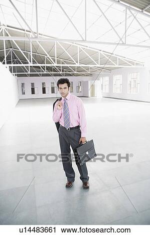 Portrait of a businessman standing and holding a briefcase in an entrance hall View Large Photo Image Stock Image - Portrait of a businessman standing and holding a briefcase in an entrance hall. Fotosearch
