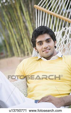 Portrait of a young man lying in a hammock and smiling View Large Photo Image Stock Image - Portrait of a young man lying in a hammock and smiling. Fotosearch
