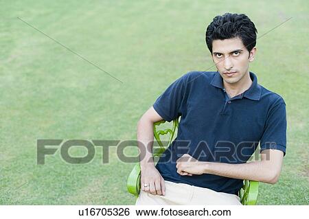 Portrait of a young man sitting on a chair View Large Photo Image Stock Photograph - Portrait of a young man sitting on a chair. Fotosearch