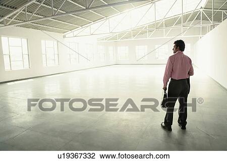 Rear view of a businessman holding a briefcase View Large Photo Image Stock Image - Rear view of a businessman holding a briefcase. Fotosearch