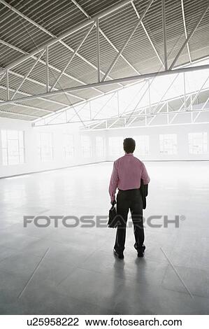 Rear view of a businessman holding a briefcase View Large Photo Image Stock Image - Rear view of a businessman holding a briefcase. Fotosearch