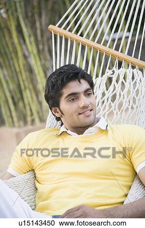Young man lying in a hammock and smiling View Large Photo Image Stock Image - Young man lying in a hammock and smiling. Fotosearch