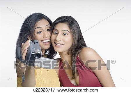 Close-up of a young woman holding a home video camera and another young woman looking at it View Large Photo Image Stock Photo - Close-up of a young woman holding a home video camera and another young woman looking at it. Fotosearch