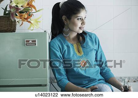 Stock Image - Close-up of a young woman leaning against a refrigerator. Fotosearch