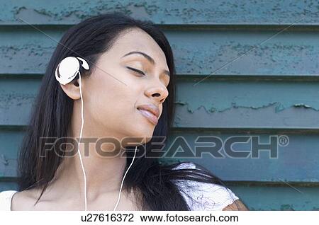 Close-up of a young woman listening to music with her eyes closed View Large Photo Image Stock Image - Close-up of a young woman listening to music with her eyes closed. Fotosearch