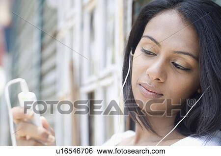 Close-up of a young woman listening to an mp3 player View Large Photo Image Stock Photograph - Close-up of a young woman listening to an mp3 player. Fotosearch