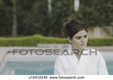 Close-up of a young woman with a facial mask standing at the poolside View Large Photo Image Stock Photo - Close-up of a young woman with a facial mask standing at the poolside. Fotosearch