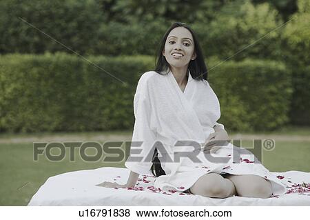 Stock Photo - Portrait of a teenage girl in a bathrobe sitting on a bed. Fotosearch
