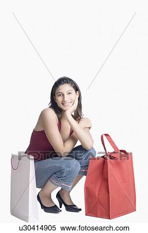 Portrait of a young woman crouching with her hand on her chin View Large Photo Image Stock Photography - Portrait of a young woman crouching with her hand on her chin. Fotosearch
