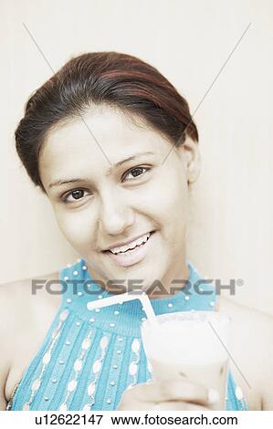 Portrait of a young woman holding a glass of milk shake View Large Photo Image Stock Photo - Portrait of a young woman holding a glass of milk shake. Fotosearch