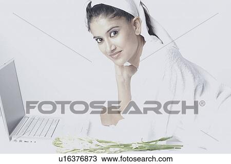 Portrait of a young woman wearing a bathrobe lying in front of a laptop View Large Photo Image Stock Image - Portrait of a young woman wearing a bathrobe lying in front of a laptop. Fotosearch