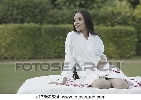 Teenage girl in a bathrobe sitting on a bed looking sideways View Large Photo Image Picture - Teenage girl in a bathrobe sitting on a bed looking sideways. Fotosearch