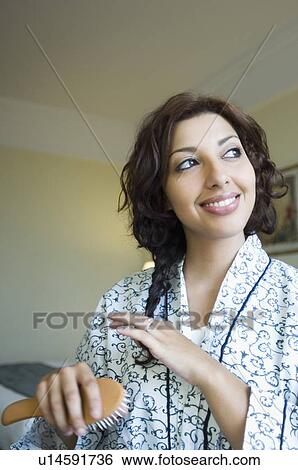 Close-up of a young woman combing her hair View Large Photo Image Stock Photograph - Close-up of a young woman combing her hair. Fotosearch