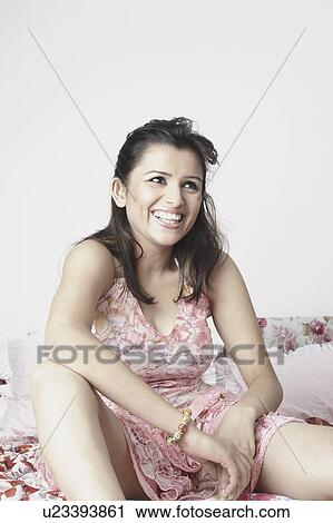 Stock Image - Close-up of a young woman sitting on the bed. Fotosearch