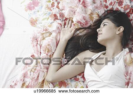 High angle view of a young woman lying on the bed View Large Photo Image Stock Photography - High angle view of a young woman lying on the bed. Fotosearch