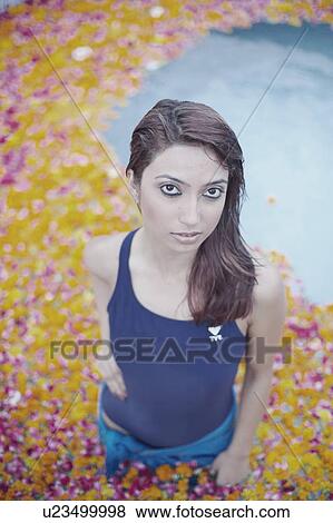 Stock Photo - High angle view of a young woman standing in a swimming pool filled with flower petals. Fotosearch