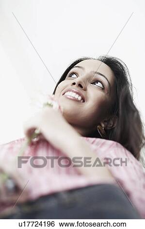 Stock Photograph - Low angle view of a teenage girl holding a flower. Fotosearch