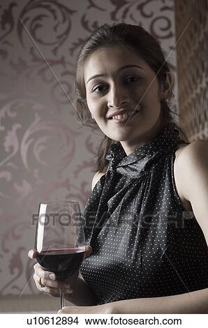 Portrait of a young woman holding a glass of wine View Large Photo Image Picture - Portrait of a young woman holding a glass of wine. Fotosearch