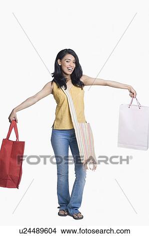 Picture - Portrait of a young woman holding shopping bags with her arm outstretched. Fotosearch