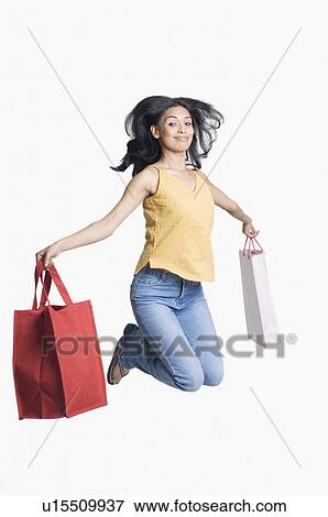Portrait of a young woman holding shopping bags and jumping View Large Photo Image Stock Photo - Portrait of a young woman holding shopping bags and jumping. Fotosearch