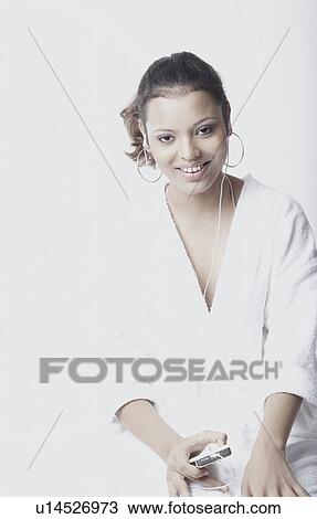 Stock Image - Portrait of a young woman wearing earphones listening to music. Fotosearch