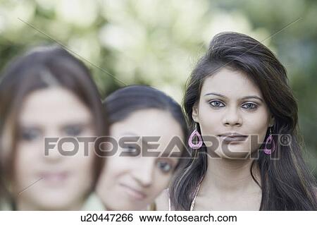 Stock Photograph - Portrait of two young women and a teenage girl standing in a row. Fotosearch