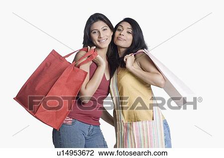 Portrait of two young women holding shopping bags and smiling View Large Photo Image Stock Image - Portrait of two young women holding shopping bags and smiling. Fotosearch