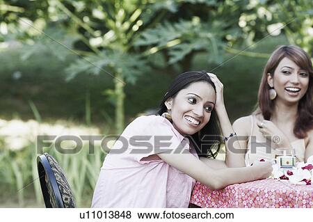Young woman and a teenage girl sitting at a table View Large Photo Image Stock Photo - Young woman and a teenage girl sitting at a table. Fotosearch