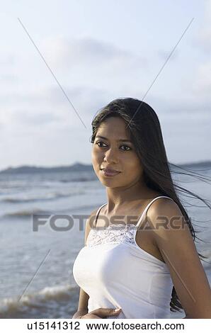 Young woman standing on the beach View Large Photo Image Stock Image - Young woman standing on the beach. Fotosearch