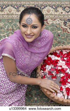 High angle view of a mid adult woman sitting on a carpet in salwar kameez with a bowl of petals View Large Photo Image Picture - High angle view of a mid adult woman sitting on a carpet in salwar kameez with a bowl of petals. Fotosearch