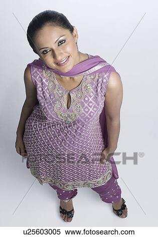Stock Photography - High angle view of a mid adult woman standing in salwar kameez and smiling. Fotosearch