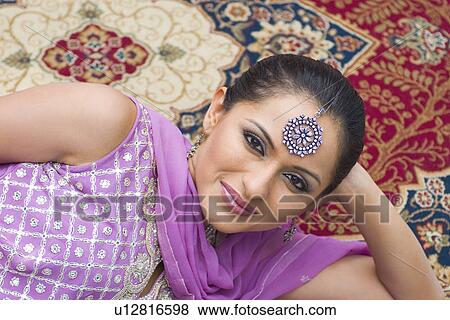 Portrait of a mid adult woman lying on a carpet in salwar kameez View Large Photo Image Stock Photo - Portrait of a mid adult woman lying on a carpet in salwar kameez. Fotosearch