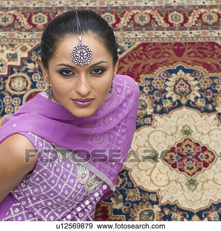 Portrait of a mid adult woman sitting on a carpet in salwar kameez View Large Photo Image Stock Photo - Portrait of a mid adult woman sitting on a carpet in salwar kameez. Fotosearch