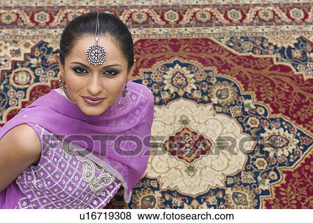 Portrait of a mid adult woman sitting on a carpet in salwar kameez View Large Photo Image Stock Photo - Portrait of a mid adult woman sitting on a carpet in salwar kameez. Fotosearch