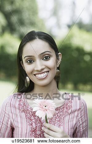 Stock Image - Portrait of a teenage girl holding a flower. Fotosearch