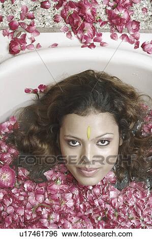 Portrait of a young woman lying in a bathtub with flower petals floating View Large Photo Image Stock Photograph - Portrait of a young woman lying in a bathtub with flower petals floating. Fotosearch