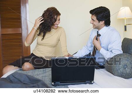 Businessman and a businesswoman sitting in front of a laptop and smiling View Large Photo Image Stock Image - Businessman and a businesswoman sitting in front of a laptop and smiling. Fotosearch