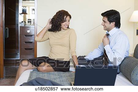 Businessman and a businesswoman sitting in front of a laptop and smiling View Large Photo Image Stock Photo - Businessman and a businesswoman sitting in front of a laptop and smiling. Fotosearch