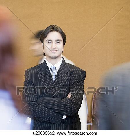 Stock Image - Businessman standing with his arms crossed and smirking. Fotosearch