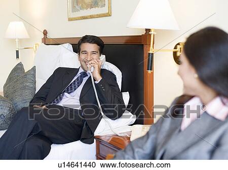 Businessman talking on the telephone with a businesswoman sitting in front of him View Large Photo Image Stock Image - Businessman talking on the telephone with a businesswoman sitting in front of him. Fotosearch