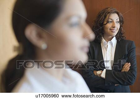 Stock Image - Businesswoman standing with her arms crossed and smiling. Fotosearch