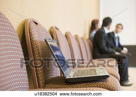 Laptop on a chair with three business executives sitting in the background View Large Photo Image Picture - Laptop on a chair with three business executives sitting in the background. Fotosearch