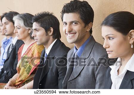 Picture - Portrait of a businessman sitting with five business executives and smiling. Fotosearch