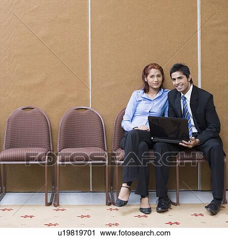 Portrait of a businessman sitting with a businesswoman and smiling View Large Photo Image Stock Image - Portrait of a businessman sitting with a businesswoman and smiling. Fotosearch