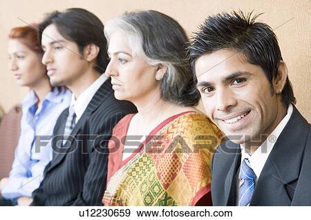 Stock Photo - Portrait of a businessman sitting with three business executives and smiling. Fotosearch
