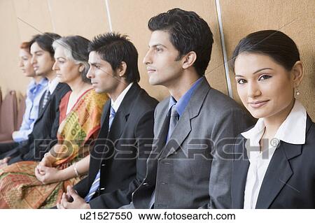 Stock Image - Portrait of a businesswoman sitting with five business executives and smiling. Fotosearch