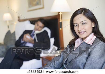 Portrait of a businesswoman smiling with a businessman talking on the telephone in the background View Large Photo Image Stock Image - Portrait of a businesswoman smiling with a businessman talking on the telephone in the background. Fotosearch