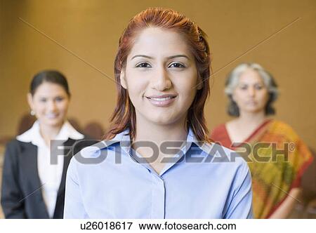 Portrait of a businesswoman smiling with two businesswomen standing behind her View Large Photo Image Stock Photo - Portrait of a businesswoman smiling with two businesswomen standing behind her. Fotosearch